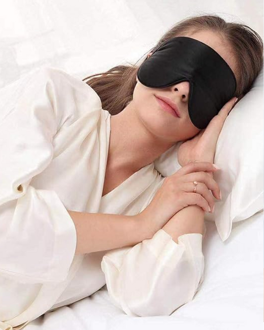 Brunette woman wearing a black eye mask lying down with her head on her hand