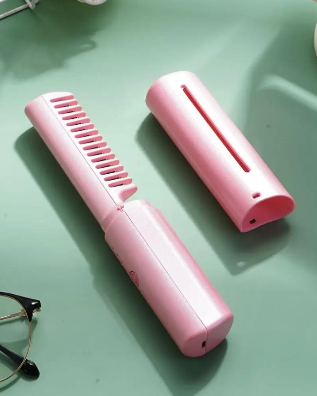 Electric comb open and closed on a green table next to a pair of glasses